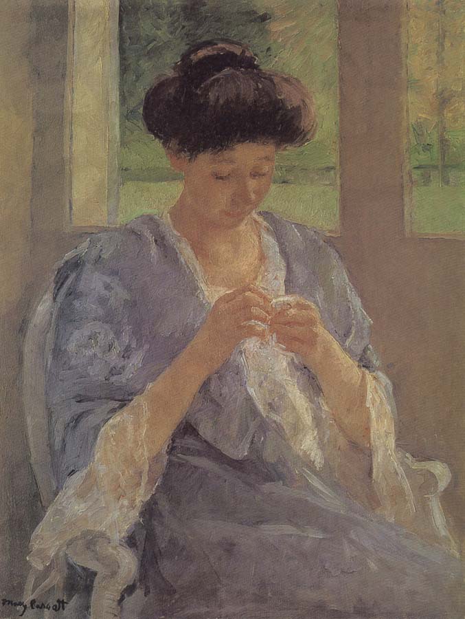 lady is sewing in front of the window